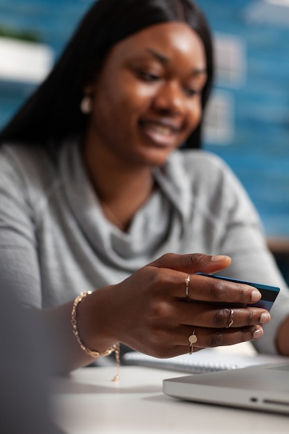 Free photo afro american woman holding economy credit card doing online shopping