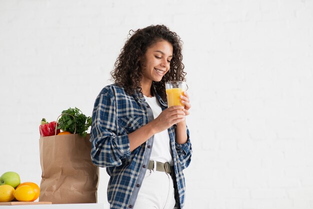 野菜の袋の隣に座っているアフロアメリカンの女性