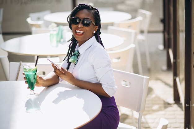 Afro american woman with phone drinking in a cafe