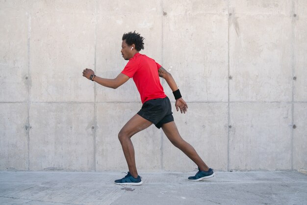 路上で屋外で走ったり運動したりするアフロアスレチック男。スポーツと健康的なライフスタイルのコンセプト。