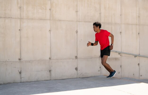 Afro athletic man running and doing exercise outdoors on the street