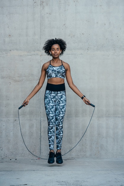 Foto gratuita donna atletica afro che fa esercizio e che salta la corda all'aperto. sport e stile di vita sano.