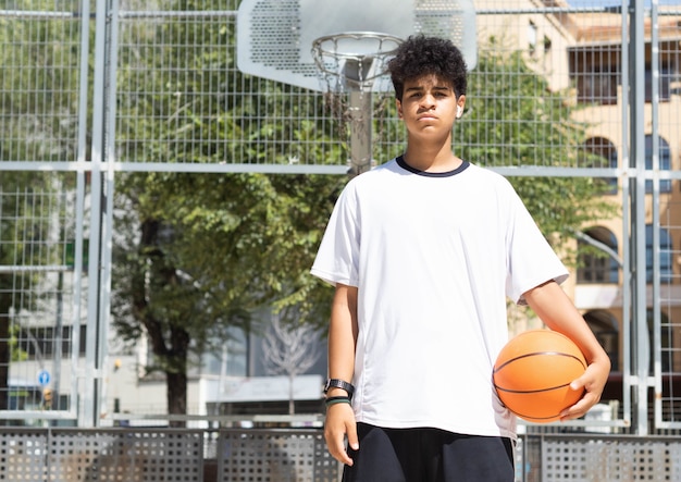 Afro teenage boy with ball in basketball court