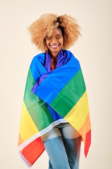 아프리카 여성은 고립된 배경에 lgbt 프라이드 깃발로 덮인 채 웃고 있습니다. lgbtq 커뮤니티 및 권리 개념입니다.