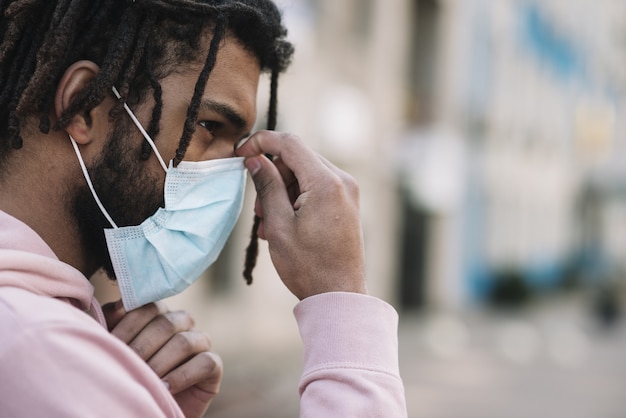 Foto gratuita uomo afroamericano che ripara maschera medica