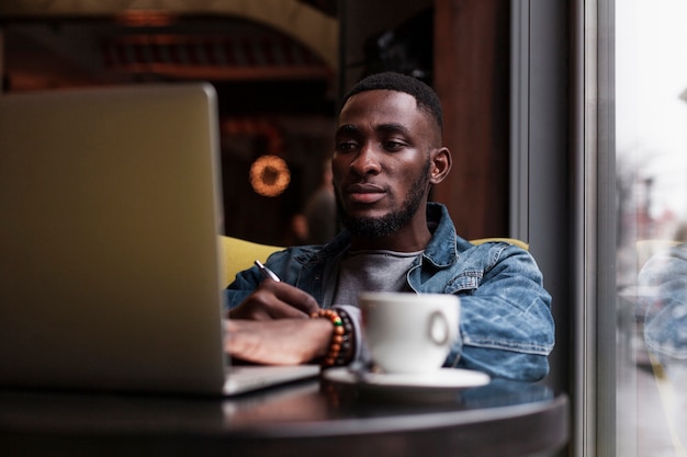 Uomo afroamericano che esamina computer portatile