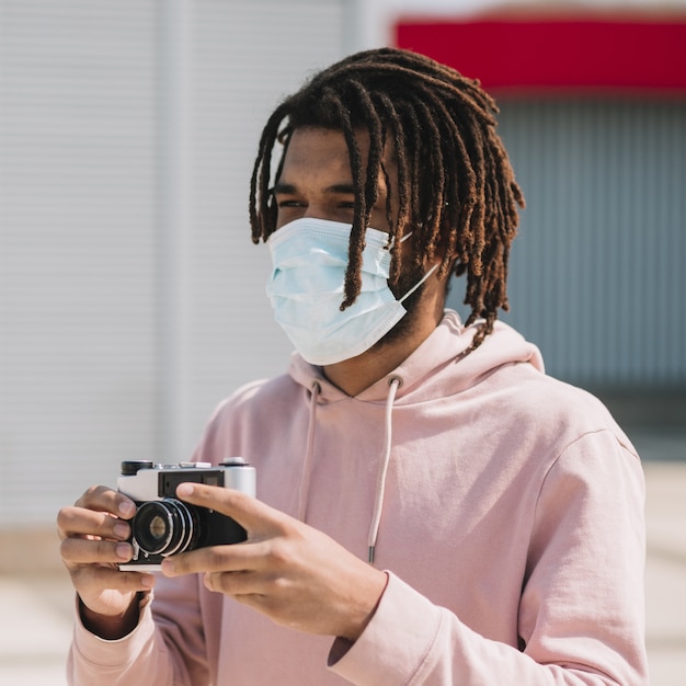 Бесплатное фото Афроамериканский фотограф в медицинской маске