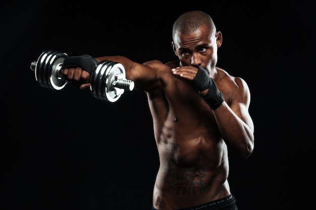 Afroamerican sports man posing like a fight with dumbbells