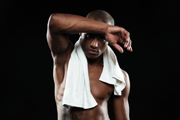 Afroamerican sports man with white towel on his shoulders resting after workout