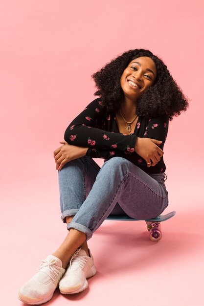 Afroamerican woman sitting on skateboard