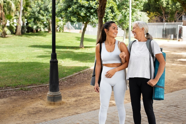 Age difference female friends meeting up for yoga outdoors