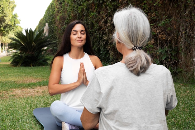 Age difference female friends meeting up for yoga outdoors