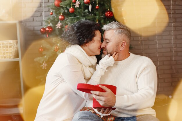 年齢と人の概念。自宅で年配のカップル。白いニットのセーターを着た女性。