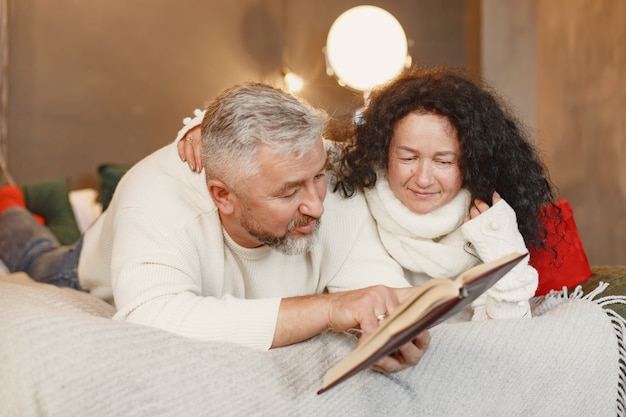 Age and people concept . Senior couple at home. Woman in a white knited sweater.