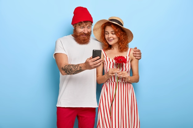 スマートフォンの時代。若い幸せなカップルはスマートフォンを介してオンラインコンテンツを見る