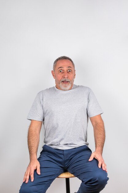 Aged amazed man on chair 