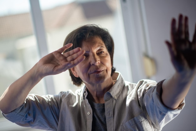 Free photo aged asian woman doing qigong exercise. serious brunette woman in shirt moving arms in gym. taijiquan concept