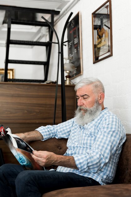 Aged client reading magazine in barber shop