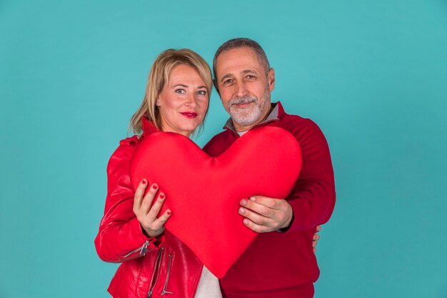 Aged couple holding toy symbol of heart