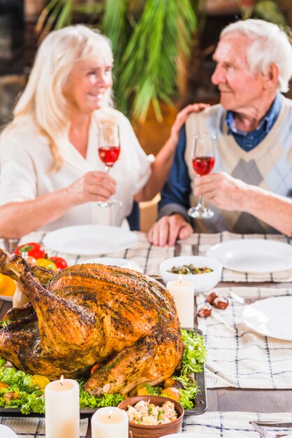 Пожилая пара сидит за столом с жареным цыпленком