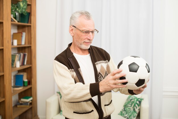 Aged man holding ball in room