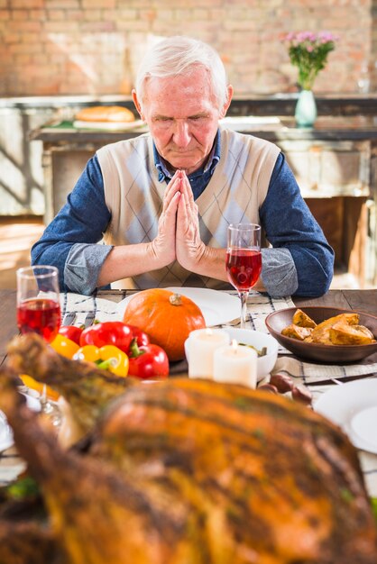 Aged man praying at table