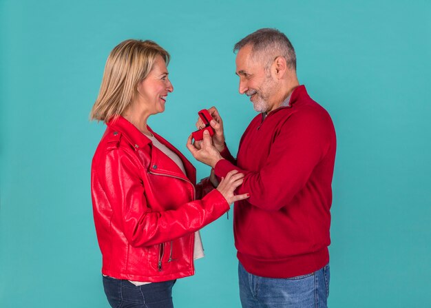 Aged man presenting jewellery box to amazed woman