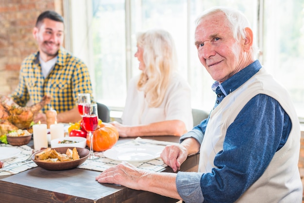 Aged man sitting at table near grey woman and young male