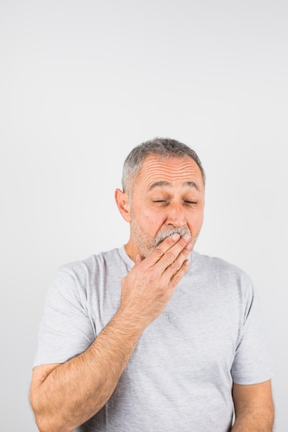 Aged man yawning covering  his mouth