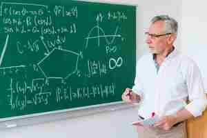 Foto gratuita insegnante di matematica invecchiato accanto alla lavagna