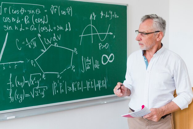 Aged math teacher next to chalkboard