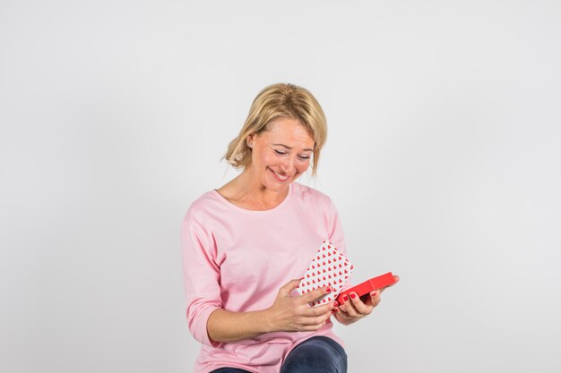 Aged smiling woman in rose blouse with present box