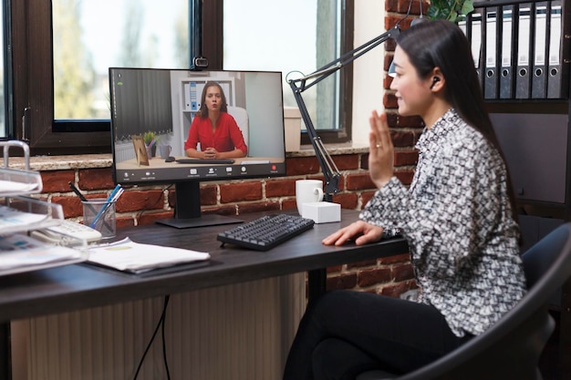 Free photo agency asian analyst in digital videocall conference with accountant talking about revenue documentation. businesswoman briefing team leader about failed strategy and unfinished presentation.