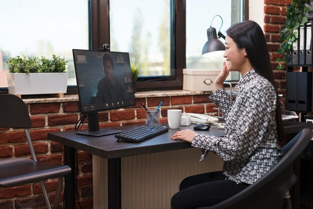 Agency office worker in virtual remote video conference with accounting manager talking about business plan. Asian team leader in internet online call conversation with agency colleague.