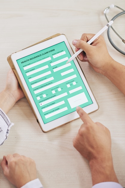 Бесплатное фото Агент заполняет форму медицинского страхования с пациентом