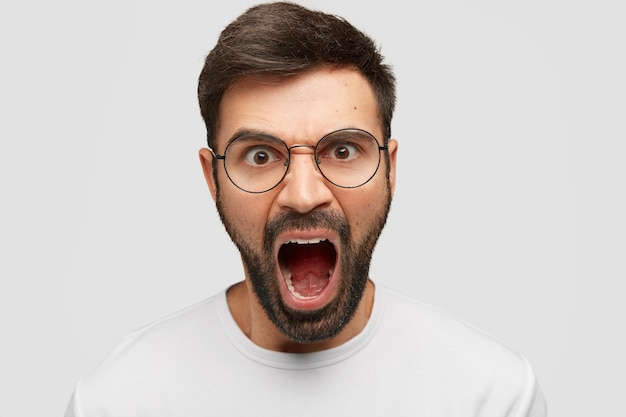 Free photo aggressive attractive man shouts furiously, being annoyed with bad service, argues with director of company