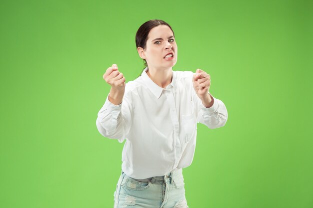 Aggressive business woman standing isolated on trendy green studio wall