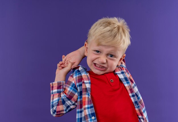 An aggressive cute little boy with blonde hair wearing checked shirt looking