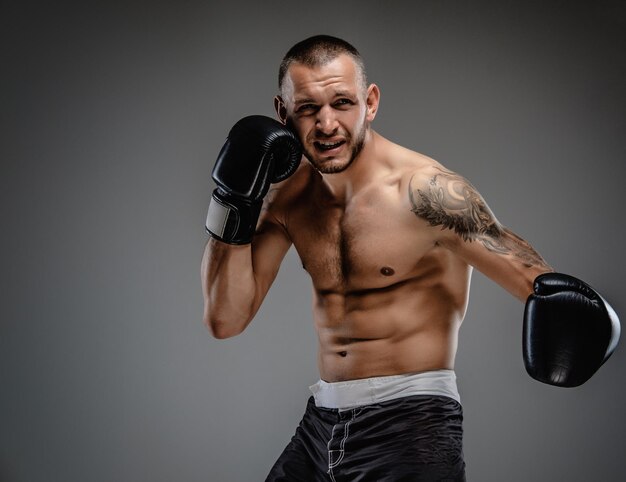 Agressive tattooed fighter isolated on a grey background.