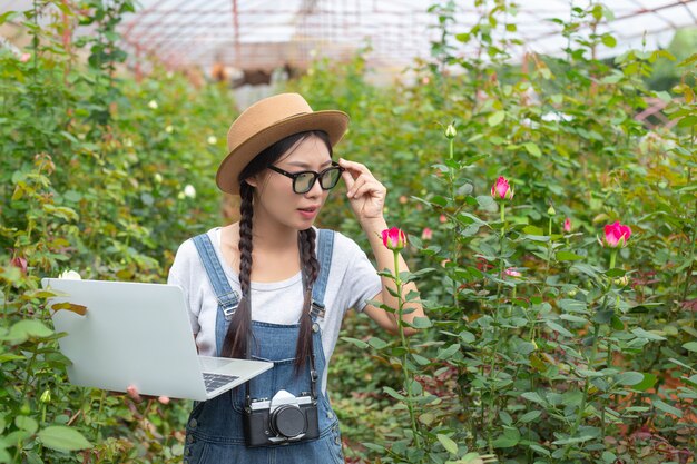 バラ園でタブレットを保持している農業の女性。