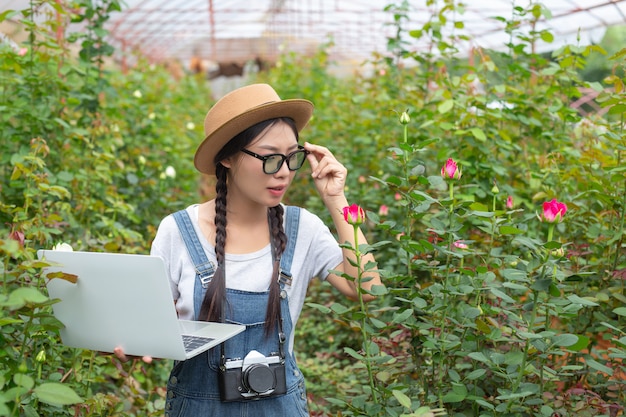 Agricultural woman holding a tablet in the rose garden.