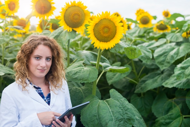 Agronomist scientist in white suit holding digital tablet in the field