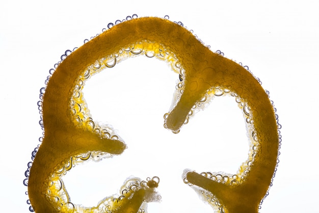 Бесплатное фото Воздушные пузыри нарезать ломтик желтого перца в воде на белом фоне
