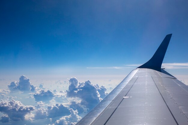 Крыло самолета в голубом облачном небе. вид из окна самолета в солнечный день. место для вашего текста. концепция путешествий и транспорта.