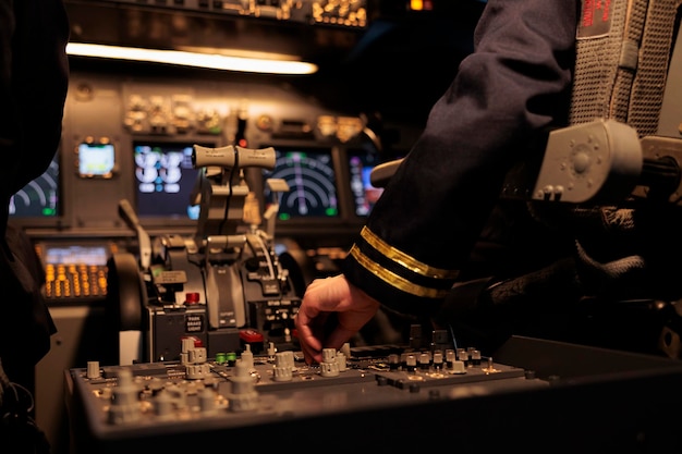 Aircrew member using control panel command on dashboard navigation to fly ariplane in cockpit. Female airliner flying plane in cabin with power engine and switch lever. Close up.