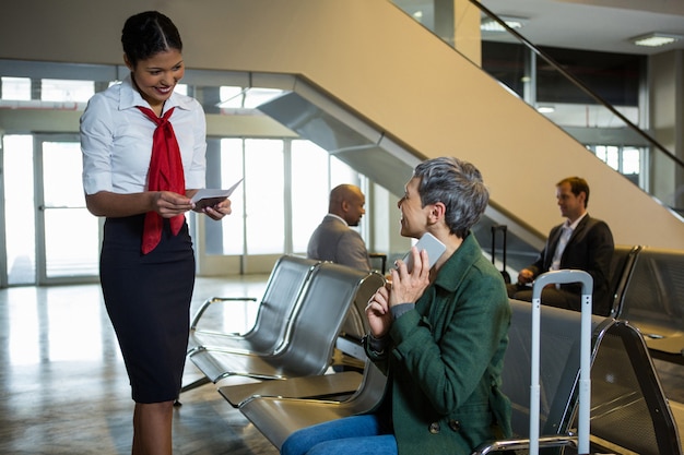 Airline check-in attendant checking passport at check-in waiting area