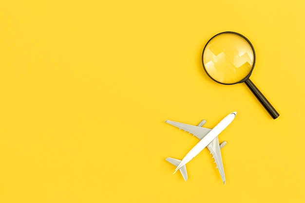 Free photo airplane model and magnifier on yellow background flat lay