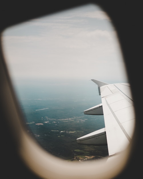 Окно самолета с видом на зеленые поля сверху и правое крыло