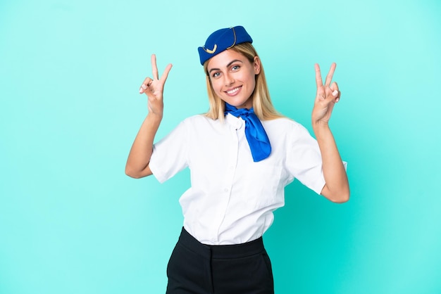 Стюардесса самолета уругвайская женщина изолирована на синем фоне, показывая знак победы обеими руками