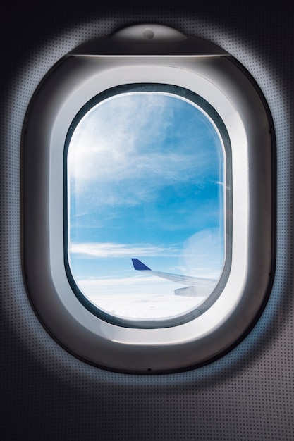 airplane window with blue sky and wing